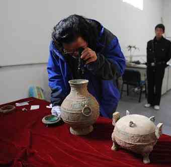Liu Daiyun, a Shaanxi Provincial Archeological Institute official, examines the recently discovered bronze pot, which contains an odorless liquid, in Xi'an, northwest China's Shaanxi Province, Dec. 10, 2010. A 2,400-year old bronze vessel containing soup with bones has been discovered recently in a tomb excavated in Xi'an. The vessel is 20 centimeters tall and has a 24.5 centimeters diameter. The archeologists also unearthed a bronze pot containing an odorless liquid, which may be ancient wine.
