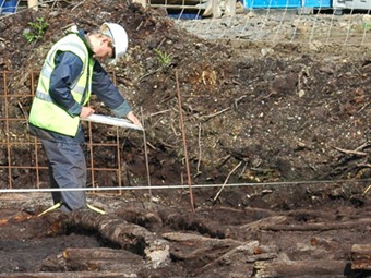 An Irish archaeologist at work drawing hand plans on site.