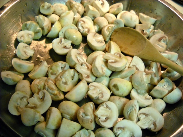 quartered fresh mushrooms in pan with olive oil cooking 