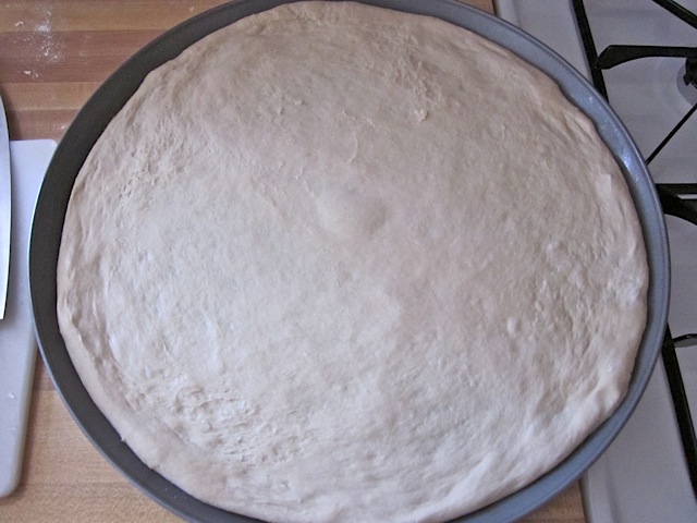 Dough stretched out and put on pizza pan 