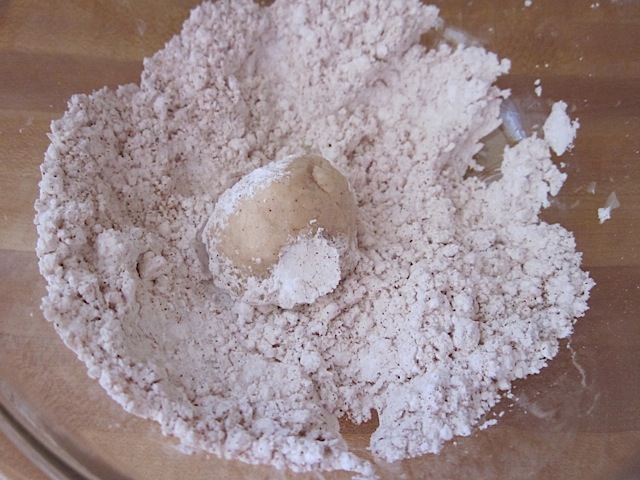 dough ball being rolled in sugar coat in mixing bowl 