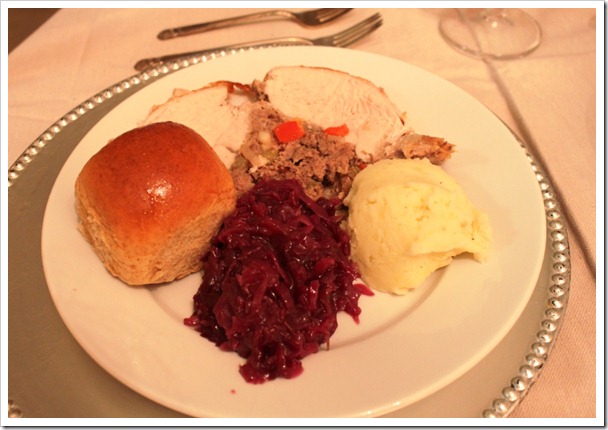slice of roasted turkey with mashed potatoes, cranberries, stuffing and a bread roll. 