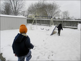 Boys running to play in the snow in the backyard.