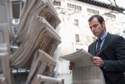 The media and its role in conflicts. A businessman reading a local newspaper.
