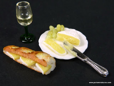 Miniature Baguette filled with ham and brie cheese accompanied by a plate of brie with grapes