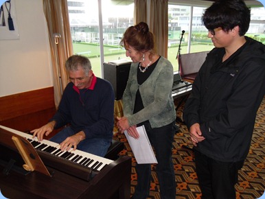 Claude Moffat trying out the Clavinova with Delyse Whorwood and her house guest from Mainland China, Ben, watching on.