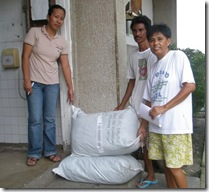 BFS Admin Asst. Ms Vivian Jatulan (leftmost) turns-over two sacks of goods to the representatives of the Pipindan Parish Mini Pastoral Council for distribution in their barangay