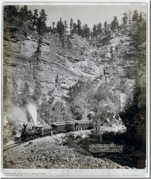 Title: "Giant Bluff." Elk Canyon on Black Hills and Ft. P. R.R.
A two-car train in front of a steep cliff; several passengers are posing in front of the train. 1890.
Repository: Library of Congress Prints and Photographs Division Washington, D.C. 20540