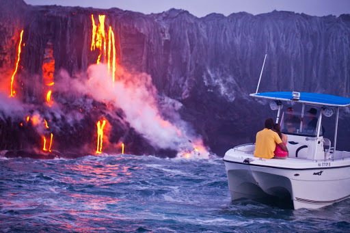 A couple watches a volcano's magma stream into the ocean on the Big Island of Hawaii. 