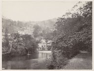 Panoramisch uitzicht op huizen tegen een heuvelrug aan een water in Matlock, op de voorgrond een overgroeid pad