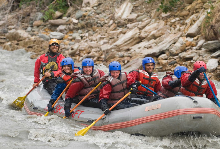 In smaller rafts, everyone paddles through white-water rapids in Denali National Park, Alaska.