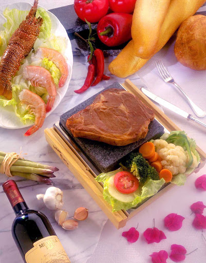 Visitors to Aruba can enjoy a meal of steak, lobster, shrimp, greens and peppers, complemented by a glass of red wine.
