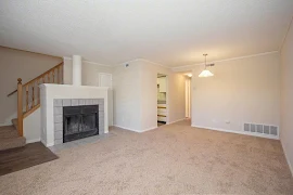 Townhome living room with plush carpet, and neutral walls, featuring a fireplace