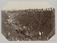 Gezicht op een gat veroorzaakt door een dynamiet explosie, omringd door toeschouwers