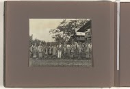 Groepsfoto met centraal een man in witte broek