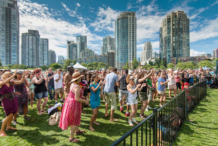 The crowd at the Vancouver International Jazz Festival dances and sings with Yaletown in the background.