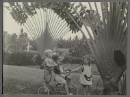 Klaas en Tiny Kleiterp en een onbekende kleuter (links) spelend met een driewieler in een tuin in Singkawang