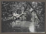 Man zittend op een boomtak boven water