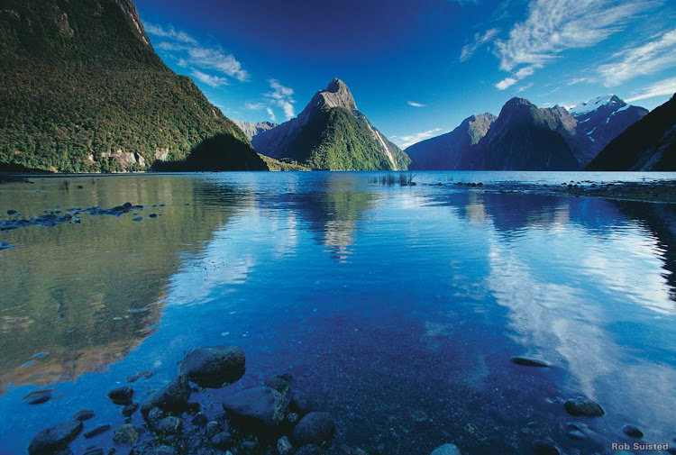 Mitre Peak takes centre stage in this perfect view of Milford Sound in summer.  Carved by glaciers over thousands of years, Fiordland is a world of deep waters, tall peaks and waterfalls.