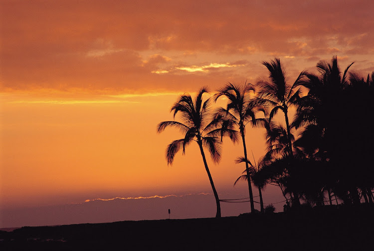 Kailua Bay on the windward coast of Oahu at twilight The remains of Ahuena Heiau, where sacrifices were offered to the gods in ancient times, are said to be found in the coconut grove in the foreground.