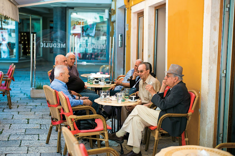 Local residents converse over coffee and drinks at a café in Croatia, one of the stops along a Mediterranean itinerary aboard Tere Moana.