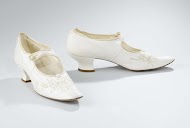 Bruidsschoen van wit glacé-leer, op het voorblad met geborduurde crème takjes en witkralen bloemen; afgeronde zeer spitse neus, Pompadourhak met leer overtrokken; wreefbandje