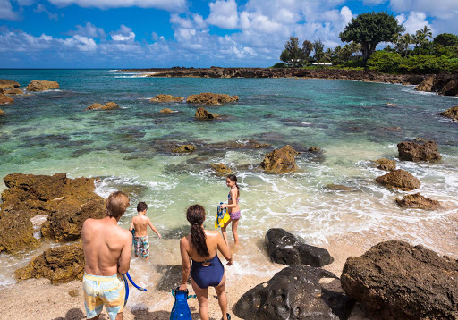 A family on the beach prepares to snorkel a North Shore cove on Oahu. 