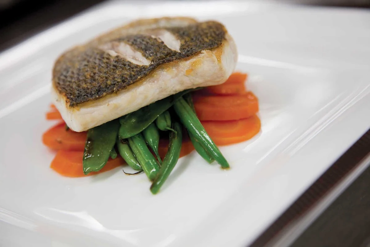 Cunard-Queen-Mary-2-dining-entree - A fish entrée with snap peas and carrots served at Queen Mary 2's Todd English restaurant, designed by renowned chef Todd English.